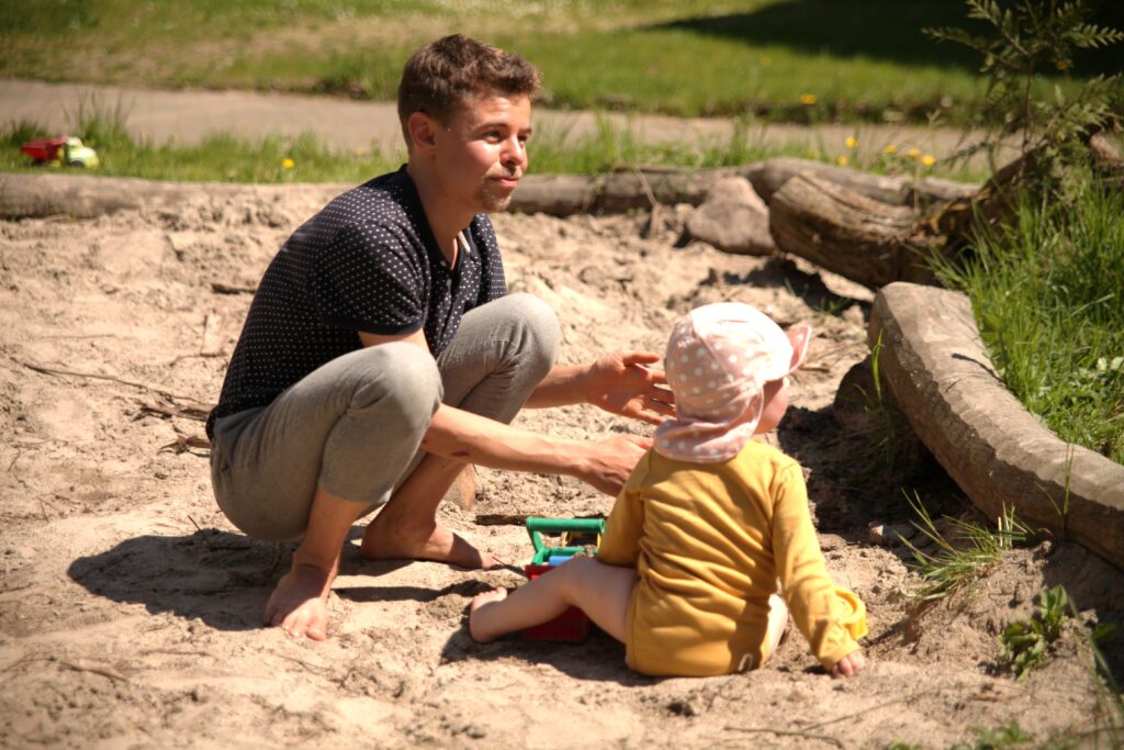 mit Kind in Sandkasten, schauen nach rechts